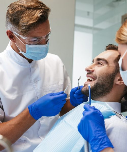Image of a handsome happy young man sitting in medical dentist center.